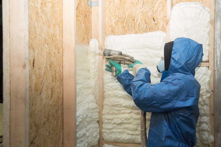 Profesional aplicando aislamiento proyectado en una estructura de madera